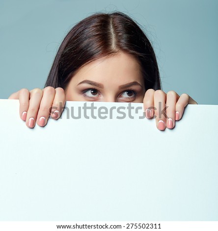 Beautiful woman standing behind, holding white blank advertising board banner, on blue background