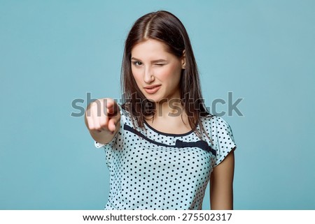 Portrait business woman standing winking over blue background and pointing at you