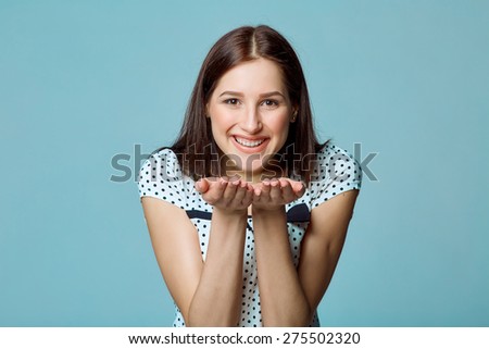 Cute young female blowing a kiss at you against blue background