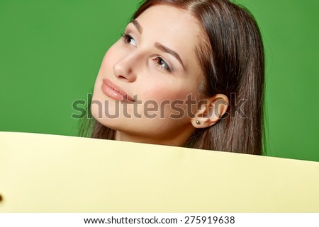 Young beautiful woman, holding yellow blank advertising board banner, on green background