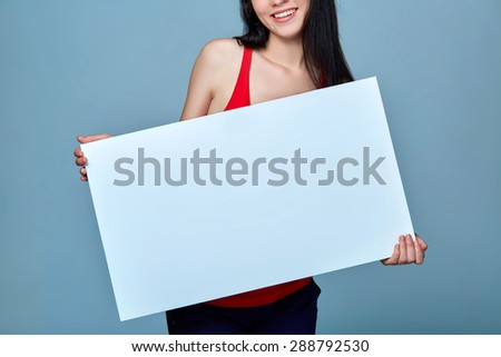 Beautiful woman standing behind, holding white blank advertising board banner, on blue background