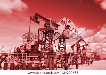 Oil and gas industry. Work of oil pump jack on a oil field in desert. Red filter