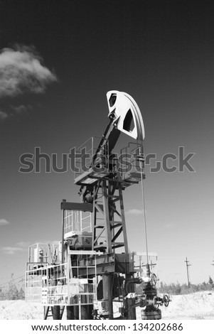 Oil and gas industry. Work of oil pump jack on a oil field in desert. Black and white photo