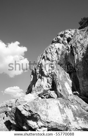 Rocky mountain. White cloud under rock. Black and white photo