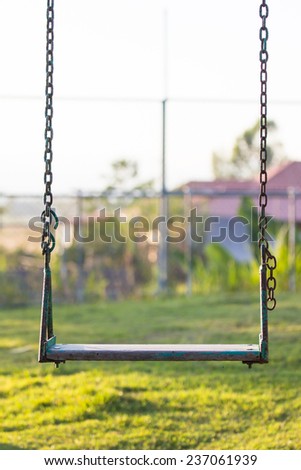 Old wooden vintage swing and rusty iron chain on playground