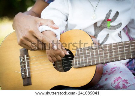 Father teach daughter play guitar