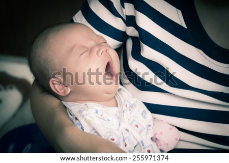 new born baby boy sleeping, yawning on mother\'s arm in vintage style