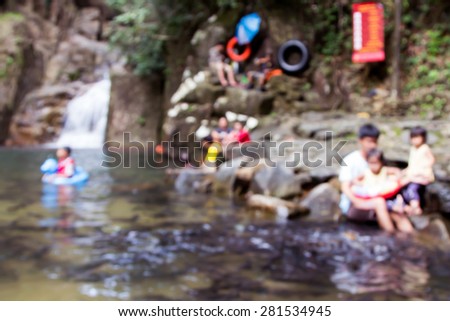 blurred image of people play water and fish feeding in public waterfall