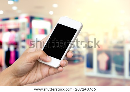 woman hand hold smart phone, tablet,cellphone on blur clothes shop background