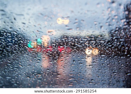 blurred image of traffic view through a car windscreen covered in rain