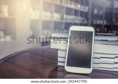 smart phone,cellphone with stack of book on blur bookshelf background in vintage color tone