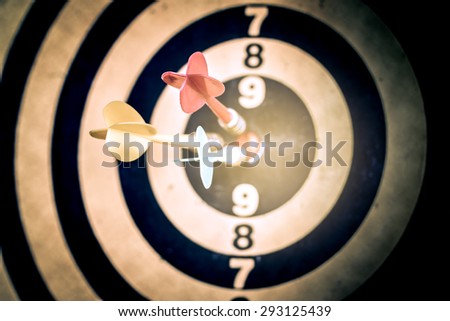 Success hitting target aim goal achievement. Three darts in target center on dartboard, vintage effect filter
