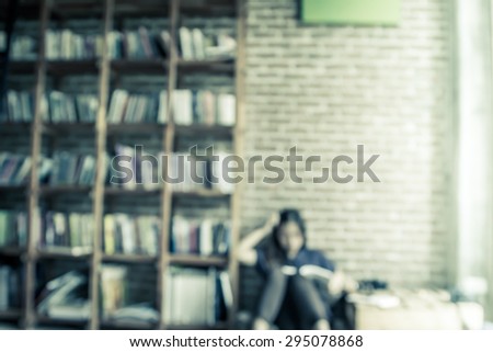 Blurred books on the shelf with people is reading a book in public library in vintage color tone