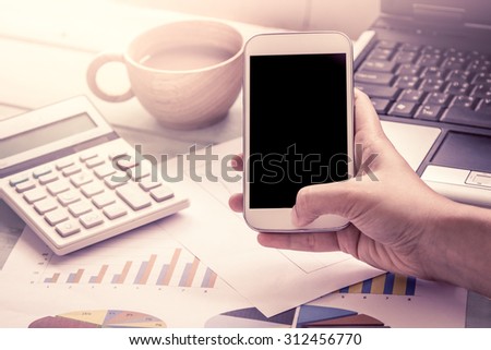 Woman hand holding smart phone,tablet,cellphone and working over desk in the office in vintage color filter