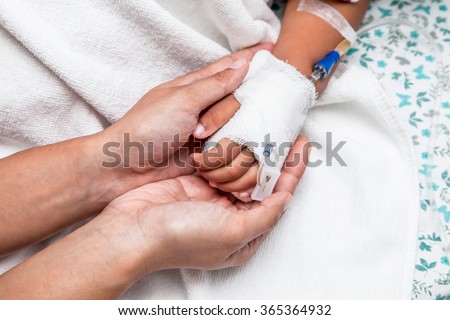 mother holding child\'s hand who have IV solution in the hospital
