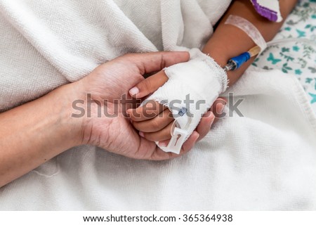 mother holding child\'s hand who have IV solution in the hospital