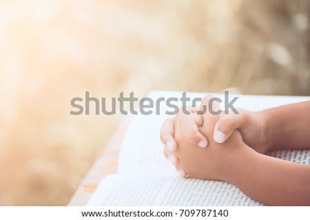Little child girl hands folded in prayer on a Holy Bible for faith,spirituality and religion concept in vintage color tone