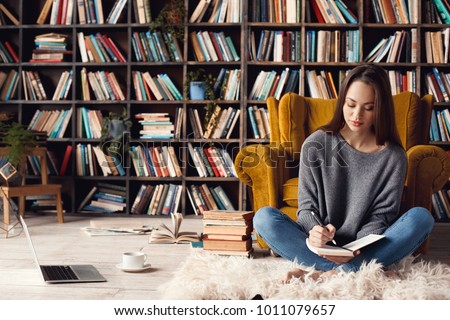 Young woman writer in library at home creative occupation sitting writing notes