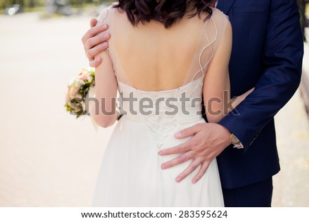 Groom in blue suit tenderly holding brides back