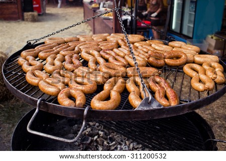 BBQ with sausages on the grill. Barbecue on the fare.Process of cooking meat on barbecue, closeup. Barbecue with meat in metal grate