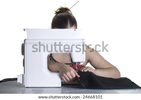 Young seamstress isolated on white is sewing on a machine; her face is hidden behind the sewing machine, only hairstyle with long hairpin is visible