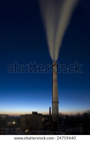 A stack of the boiler house smoking upwards on the gradient evening background