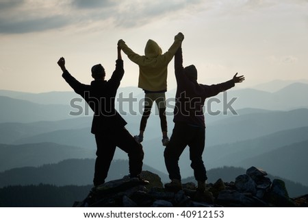 Family on top of mountain raise their hands