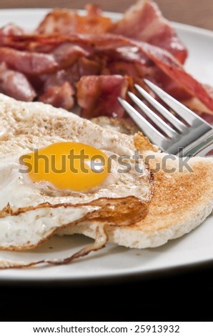 Bacon and eggs on toast served on white plate
