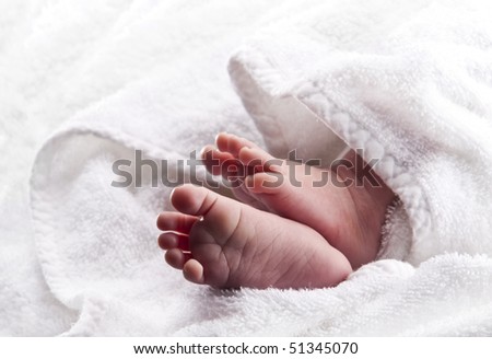 Bare baby feet wrapped in a white towel