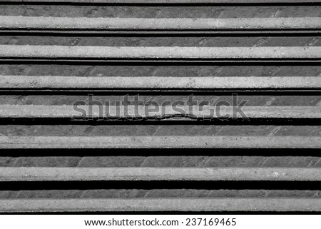 Abstract close up photo of roof tiles stacked one on top of the other. Only horizontal lines of gray are visible.