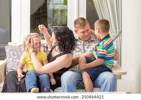 Young family sitting together on the porch, having fun.