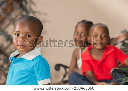 Little boy with his older brother and sister, who are twins, sitting behind him.