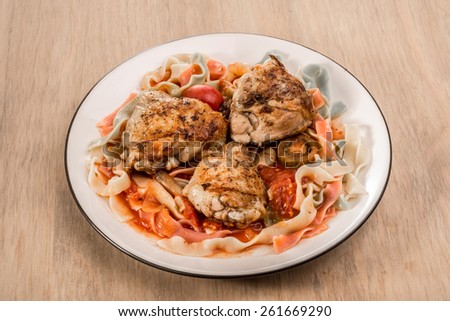 Fettuccine pasta with a tomato sauce and friend chicken on a plate.