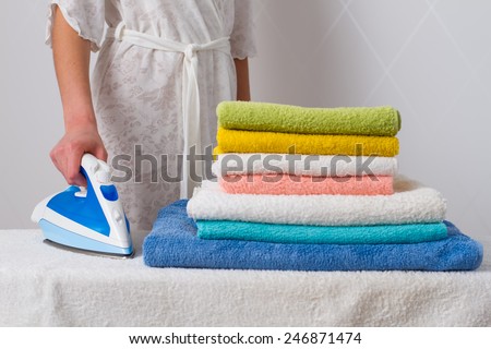 housewife  standing at the ironing board ironing towels