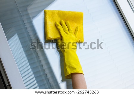 Cleaning windows with special rag in yellow gloves