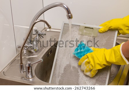 Washing grid kitchen hood in yellow gloves in the kitchen