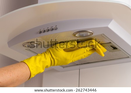 Cleaning kitchen. Washing kitchen hood in yellow gloves.