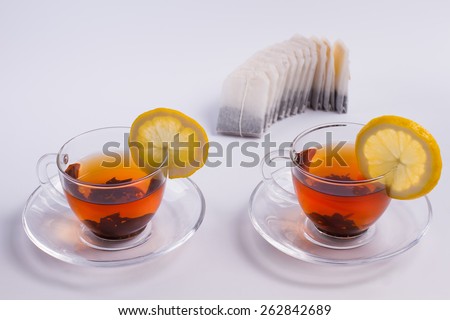 Two cups of black tea with lemon and tea bags.