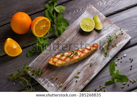 Grilled salmon steak with fresh herbs, fruits and spices on  wooden board.