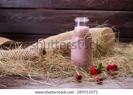 Natural rural milk in the hay with berries. Strawberry milk shake in a glass jar.