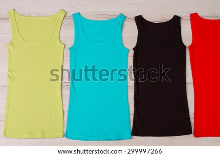 Cute summer tank tops on wooden background. Colorful T-shirts.