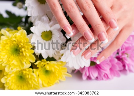 Beautiful well-groomed female fingers with manicure. Women\'s hands on the background of flowers.