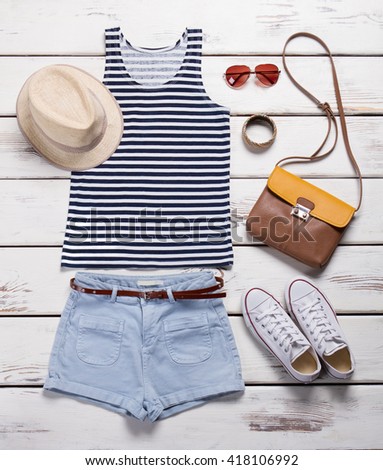 Light shorts with striped top. Girl\'s summer outfit on showcase. Summer clothing and trendy accessories. Female garments with aviator sunglasses.