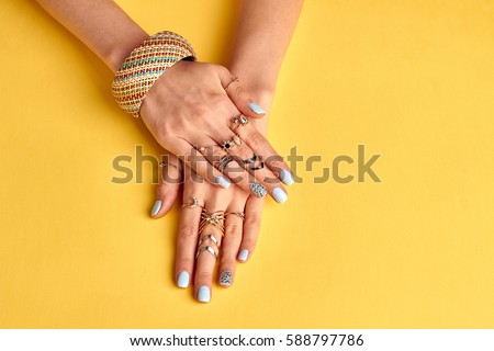 Fashionable youth bijouterie on female hands. Preparing to summer. Bijouterie and jewelry. Beautiful well-groomed female hands with nail polish.