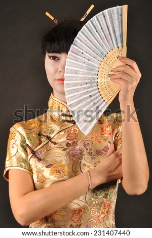 Asian style portrait of young woman with fan isolated on black background
