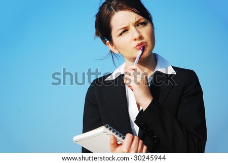 A beautiful young business woman doing her work on a notepad in front of a blue sky.