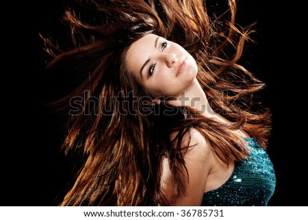 A beautiful young woman dancing with her hair in motion on a black background.