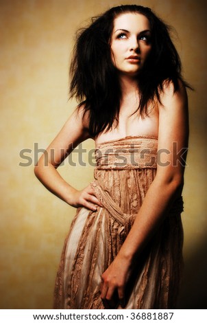 A beautiful young brunette woman posing with her arm up. Dramatic lighting, romantic feel.