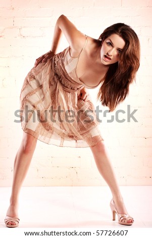 A young brunette pulling a ridiculous pose in a pretty dress.