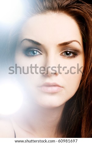 A pretty young woman with an illuminous glowing lights near her face. Beauty shot.